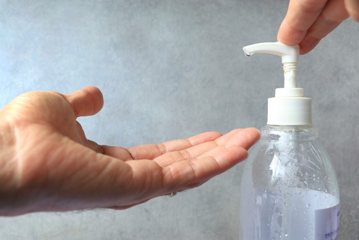 Hands with alcohol gel bottle in Sanitation and anti germ concept.