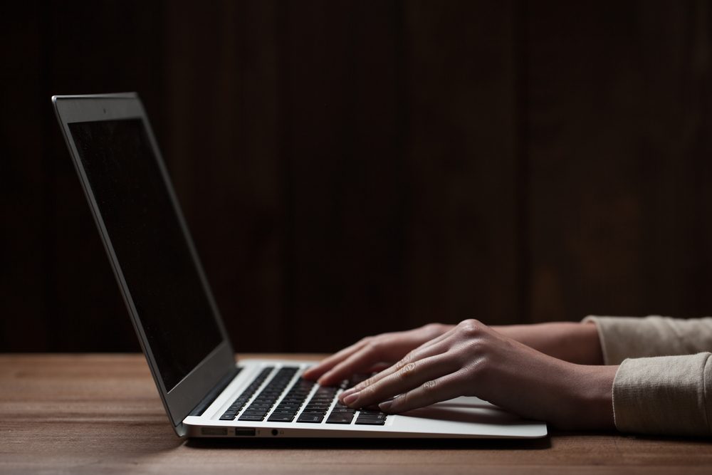 woman hands using laptop at office desk, with copy space in dark space