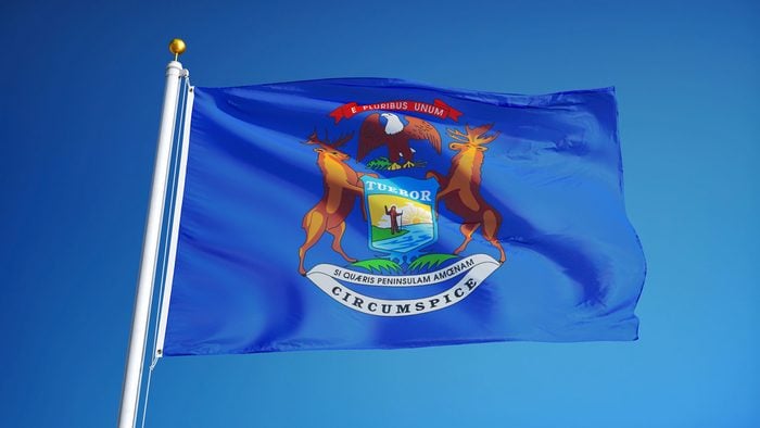 Michigan (U.S. state) flag waving against clear blue sky, close up, isolated with clipping path mask alpha channel transparency, perfect for film, news, composition