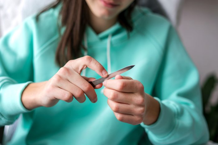 young girl handles nails with nail file close up