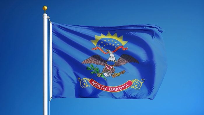 North Dakota (U.S. state) flag waving against clear blue sky, close up, isolated with clipping path mask alpha channel transparency, perfect for film, news, composition