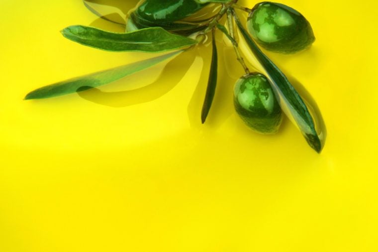 Green olive branch with olives in olive oil.
