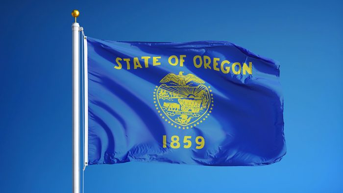 Oregon (U.S. state) flag waving against clear blue sky, close up, isolated with clipping path mask alpha channel transparency, perfect for film, news, composition