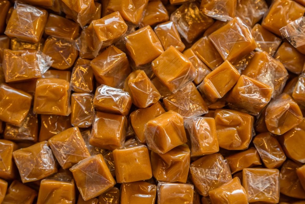 Toffee candy brown background. Caramel cubes close up