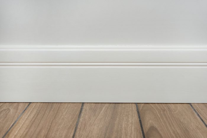 Light matte wall, white baseboard and tiles immitating hardwood flooring