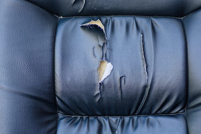 Torn car seat black leather ruptured foam rubber