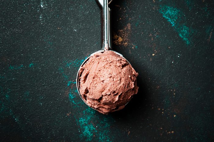 Chocolate ice cream in metal spoon for ice cream, dark background, top view