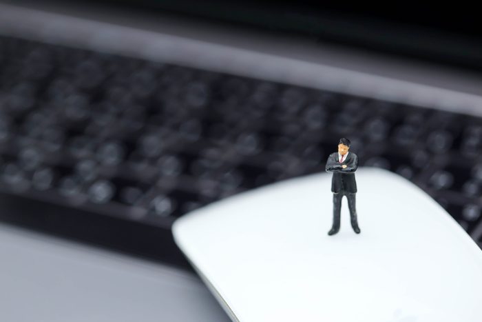 Miniature people : Businessman standing on mouse of laptop.