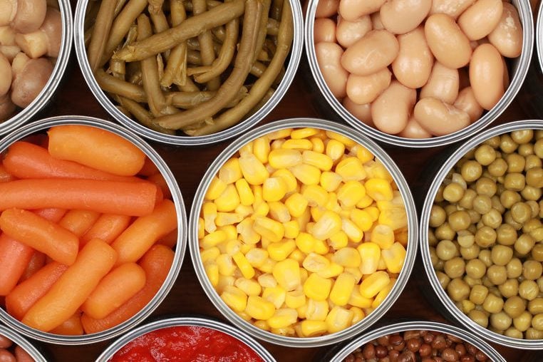 Diferentes tipos de vegetais, como milho, ervilhas e tomates em latas
