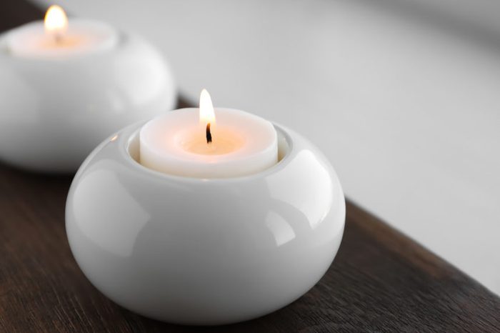 Beautiful burning wax candle in holder on table