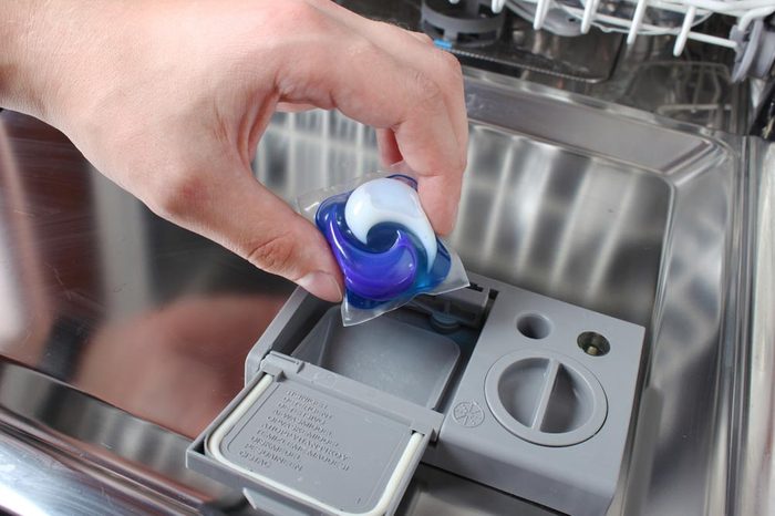 Капсула для посудомоечной машины рука держит капсулу