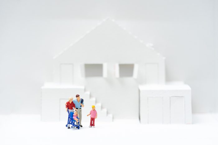 Miniature people, family standing in front of toy houses. Concept for property ladder, mortgage and real estate investment and lover.