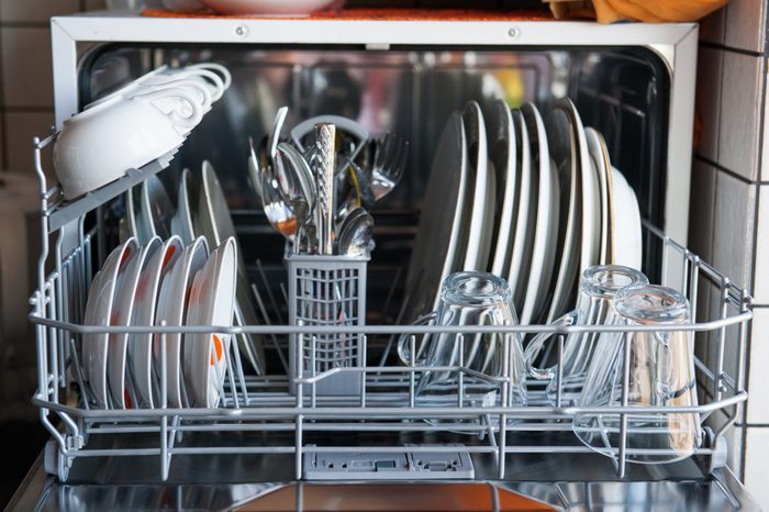 Маленькая посудомоечная машина, полная чистой посуды