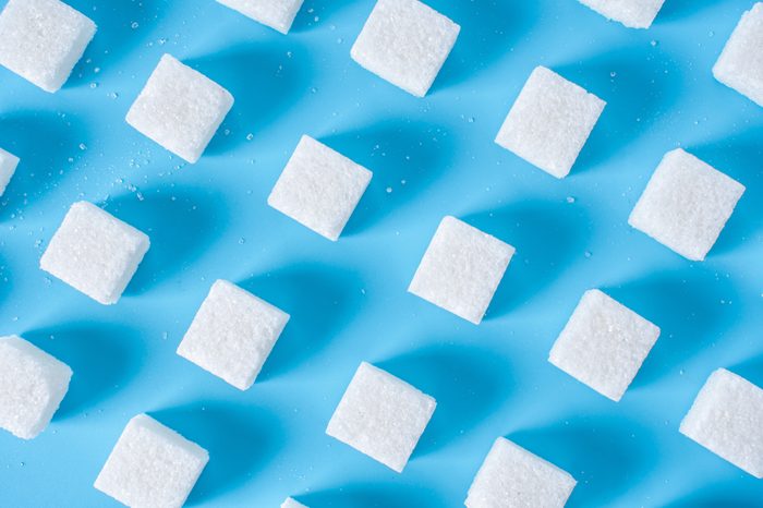 Pattern of sugar refined cubes with shadows on a blue background. The concept of harmful ingredient for confectionery