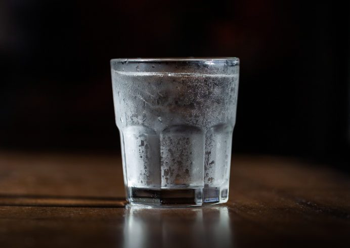 Cold water in a glass with ice on a wooden table by the window. Used for drinking to keep the body fresh. water cup dark tone