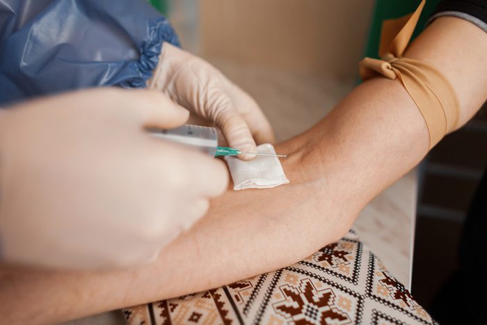 A nurse injects a flu vaccine into a young man's vein. A doctor giving an injection to a sick patient with a syringe. Close-up