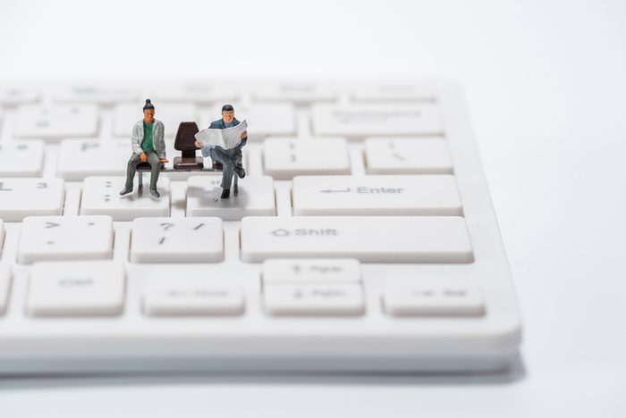 miniature people figure sitting on bench on computer keyboard background