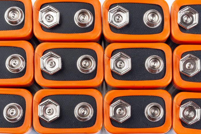 Background image of a large number of orange batteries, standing in several rows.