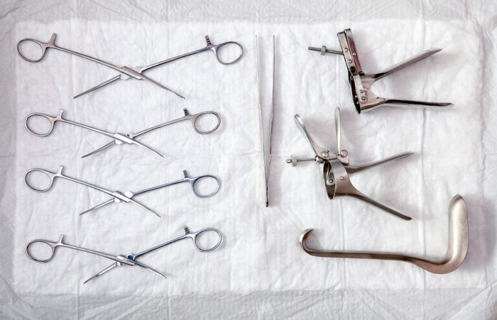 Gynecological sterile tools. A lot of instruments of gynecologist on white background. Top view.