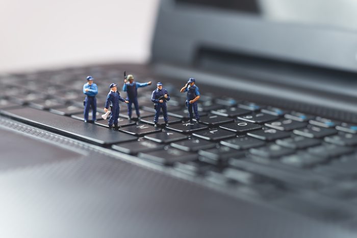 Miniature police squad protecting laptop computer. Technology concept