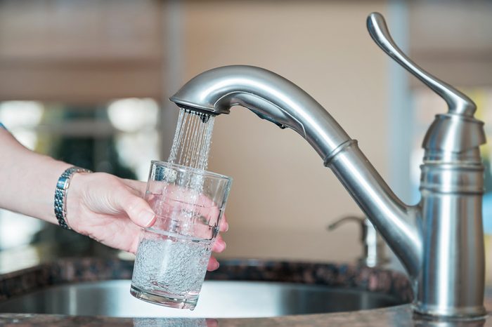 person filling up a glass of tap water