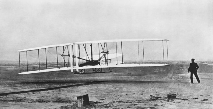 VARIOUS Kitty Hawk, North Carolina: December 17, 1903 Orville Wright flying during the first powered and sustained flight while Wilbur is on the ground at right.