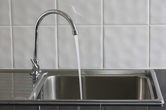 Metal faucet in a kitchen is open water