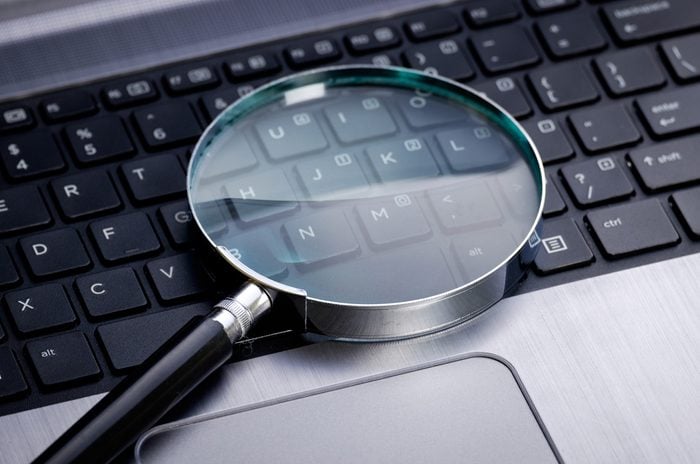 Magnifying glass on laptop keyboard; online search, online shopping, business concepts.