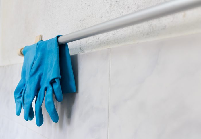 Blue glove hanging on towel rack in bathroom.