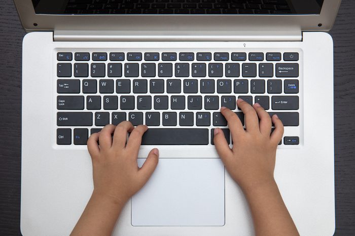 Close up aerial view of children hands typing on laptop keyboard.