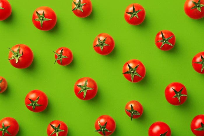 Cherry tomato pattern on a green background. Flat lay, top view