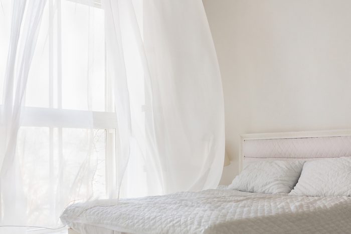 Abstract white flying curtain in white room with bed