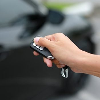 Women hand pressing the button on the remote to lock or unlock the car