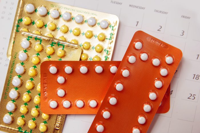 Contraceptive pill on calendar background.