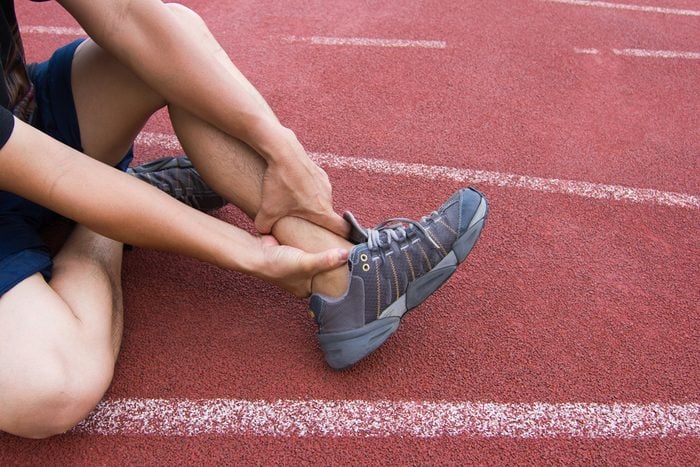 Sports Man Runner with injured ankle while training in the Stadium