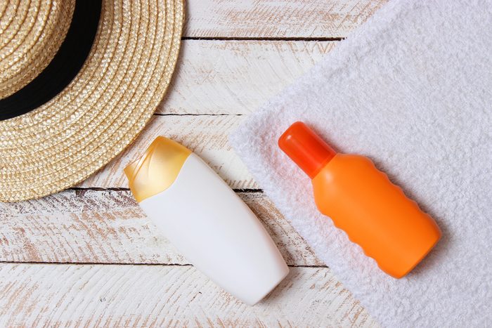 sunscreen, towel, hat, glasses on a wooden background. minimalism, the top view, flatlay 