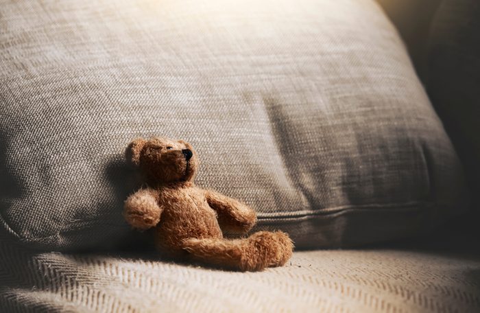 Teddy bear sitting down on sofa in retro filter, Lonely teddy bear sitting alone on couch in living room at night,Lonely concept,Lost child,International missing children's day.