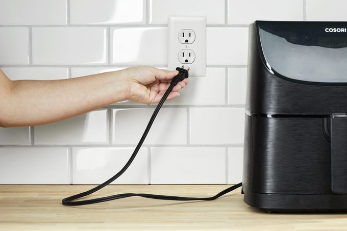 hand unplugging an air fryer from the wall