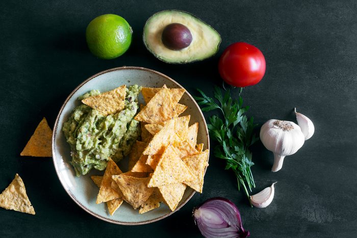 Plate of guacamole with tortilla chips and ingredients