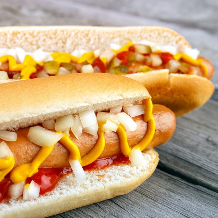 Two hot dogs with ketchup closeup , yellow mustard and onion on gray wooden surface; Shutterstock ID 263142953; Job (TFH, TOH, RD, BNB, CWM, CM): TOH