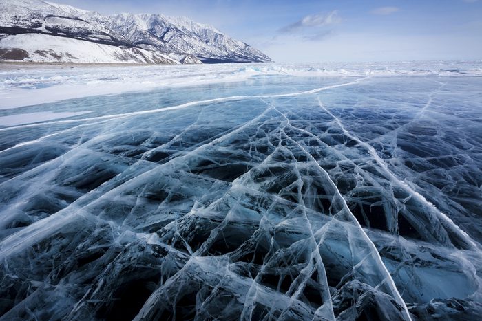 View of beautiful drawings on ice from cracks and bubbles of deep gas on surface of Baikal lake in winter, Russia