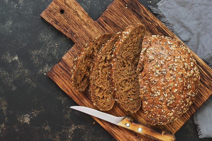 Fresh bread with sunflower seeds, sesame seeds and flax are cut into pieces on a cutting board. Top view, copy space