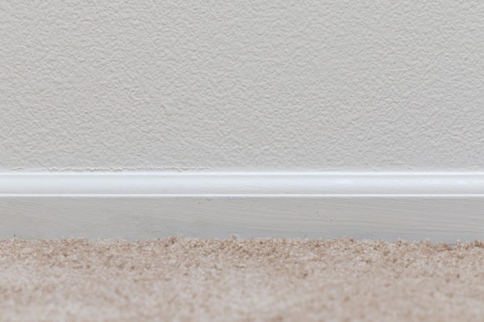 Basic floor trim up against a tan carpeted floor