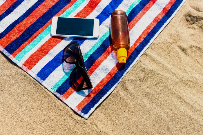 Beach Towel, mobile phone and sunscreen on the beach