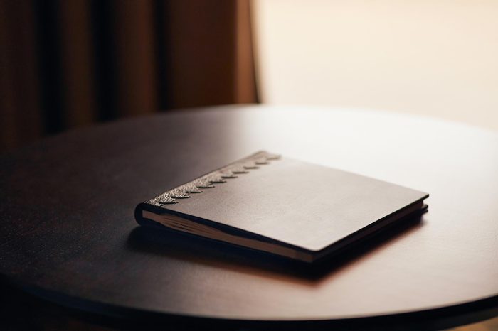 Note book with hard wooden cover on table by the window in natural light