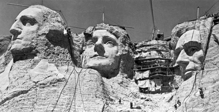 VARIOUS Mt. Rushmore, South Dakota: c. 1938. Workmen on the faces of Mount Rushmore. Roosevelt has the scaffolding over his face.