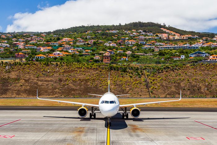 Aircraft at the airport after landing, preparing to be docked, in the background Agua de Pena village, Madeira, Portugal