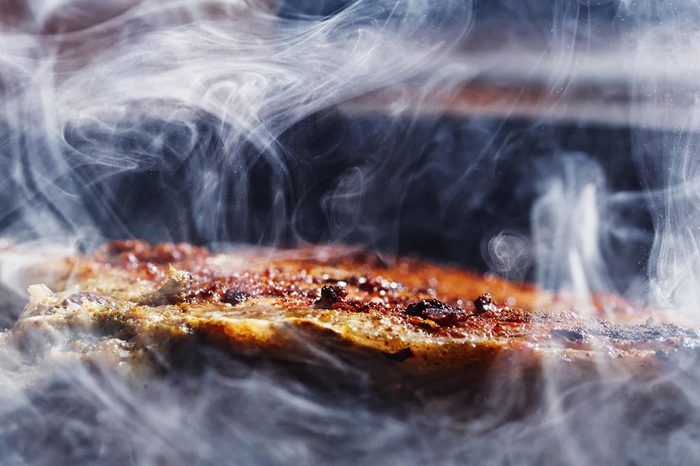 smoke and steam rise from a pork steak
