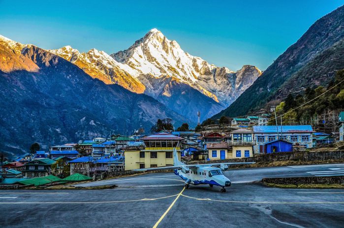Airport in Lukla with plane and mountains behind
