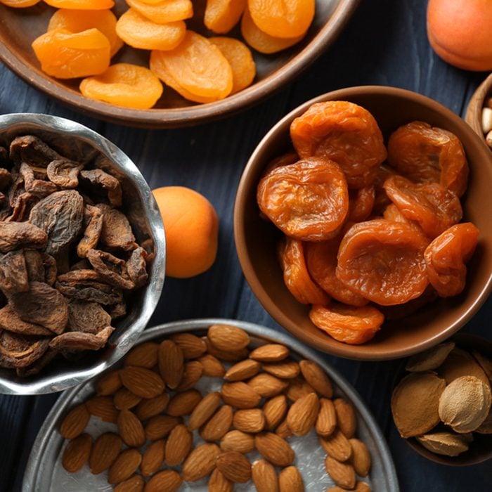 Dried apricots and nuts in different dishes on wooden table; Shutterstock ID 720334081; Job (TFH, TOH, RD, BNB, CWM, CM): TOH